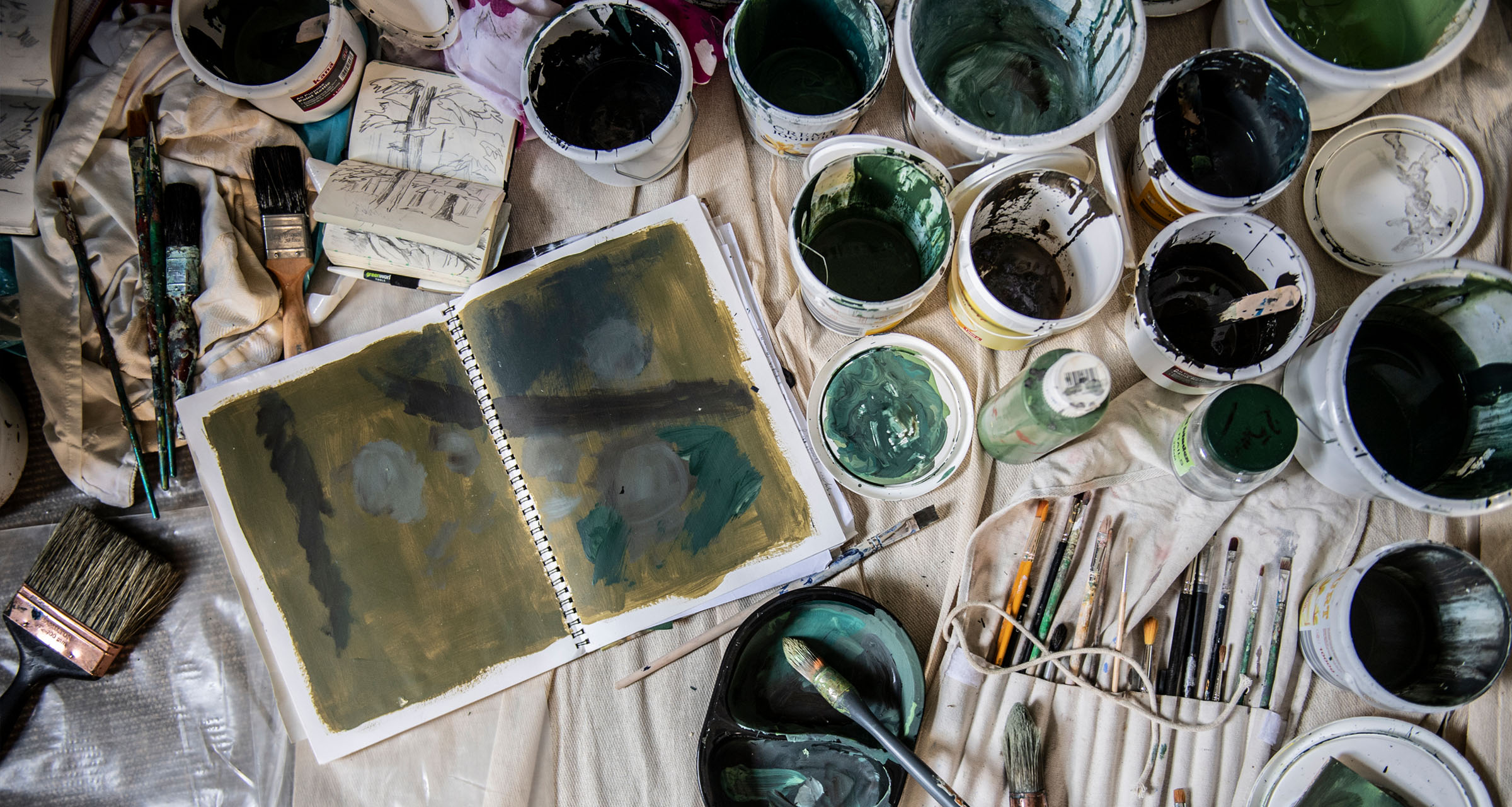 Paint pots and brushes with an open sketchbook
